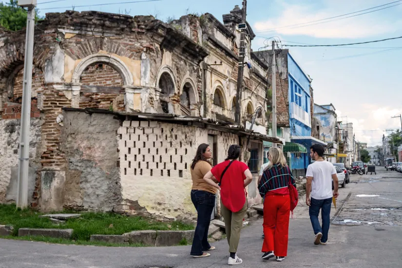 Um grupo de cinco pessoas caminha por uma rua antiga em Recife, Brasil.