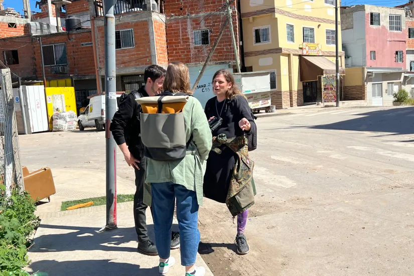 Três pessoas conversam em uma esquina na Villa 20, Buenos Aires.