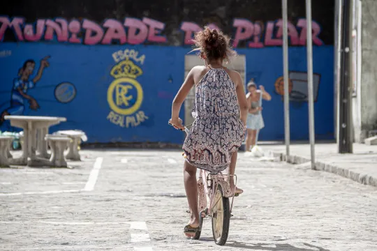 Uma jovem em uma bicicleta em um ambiente urbano.