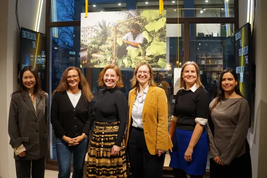 Five women pose in front of a photograph