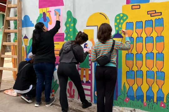 Três pessoas pintando um mural