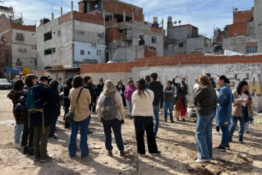 Un grupo de personas en una calle sin asfaltar de un barrio en desarrollo.