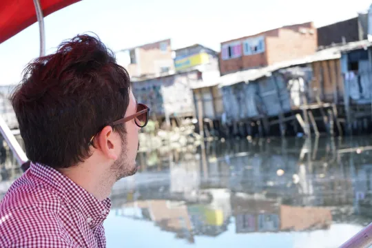 Um homem olhando casas de um barco.