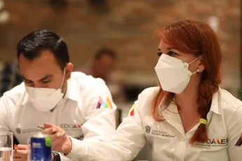 Mãos de pessoas sobre um mapa de Naucalpan aberto sobre uma mesa.