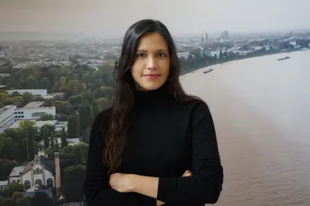 A woman standing in front of a picture of the river Rhine in Germany