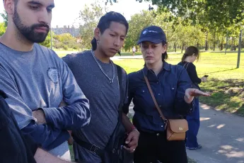 Uma mulher e dois homens olhando para algo que está acontecendo na frente deles