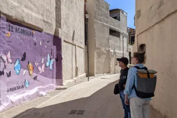 Woman and man look at a mural painting of butterflies on a purple background