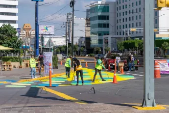 People paint bright colours onto a street