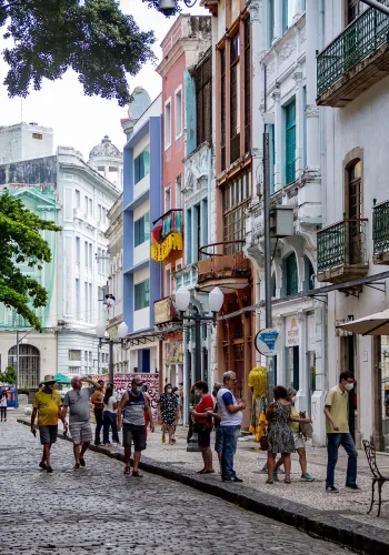 Pessoas caminhando por uma rua cheia de cores em Recife, Brasil.